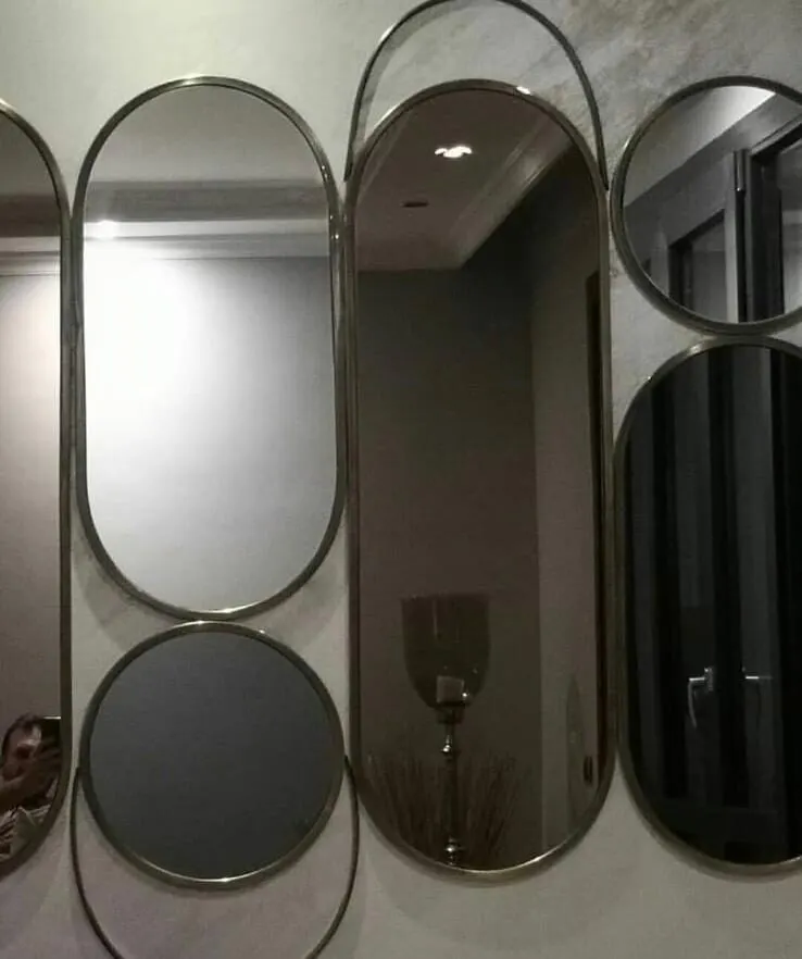 Duvarda yan yana dizilmiş, pirinç tonlu ince metal çerçeveli oval ve yuvarlak aynalar